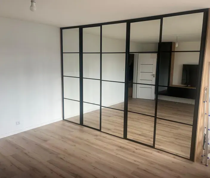Ścianka działowa w stylu loft: czarne profile, tafle szkła i lustra dzielące pokój
